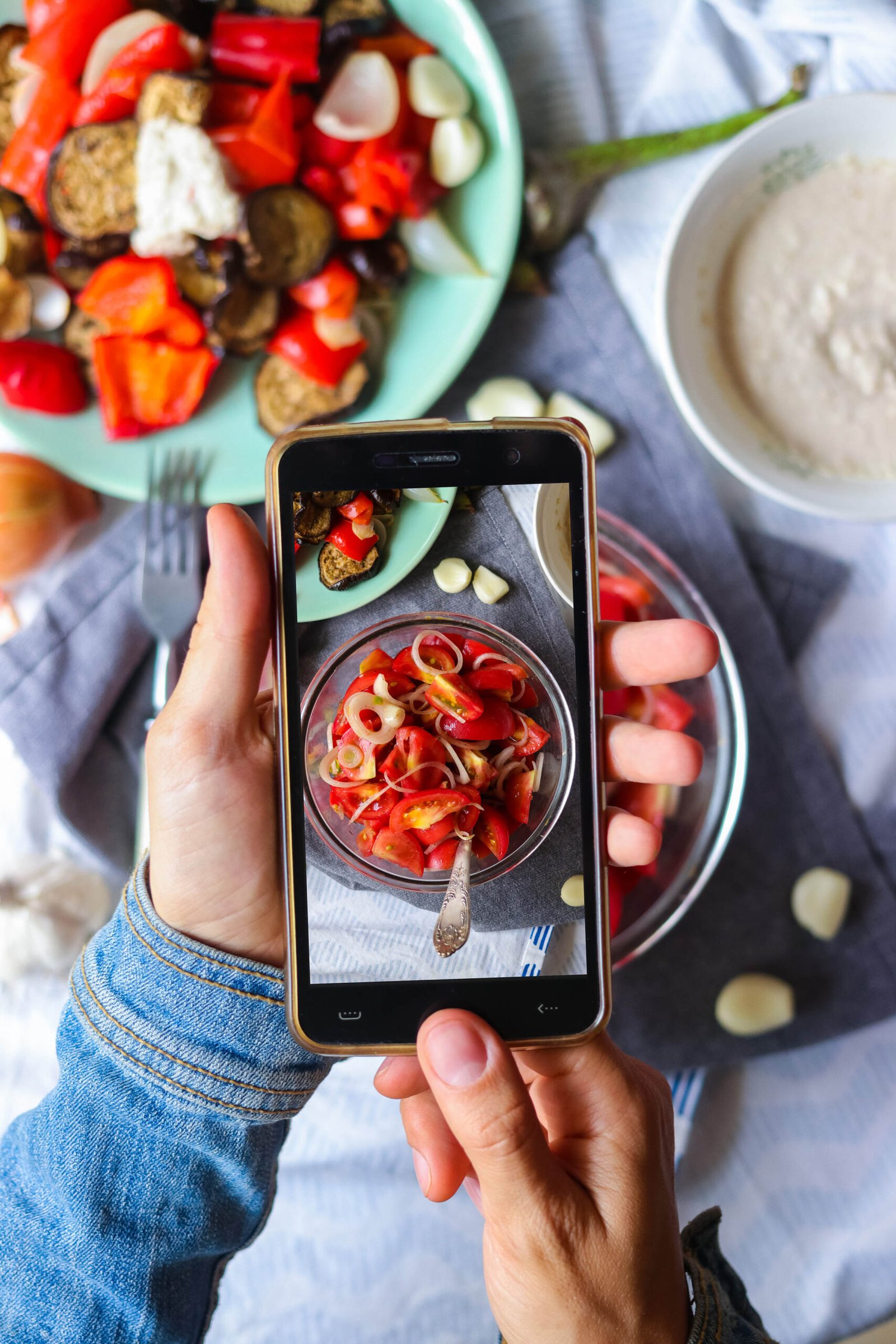 Woman hands takes smartphone food photo of fresh tomatoes salad